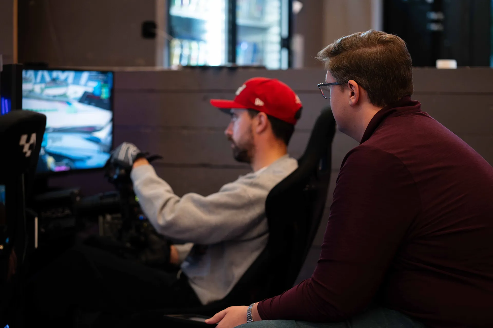 Grid Lounge staff helping a new driver get set up at the simulator